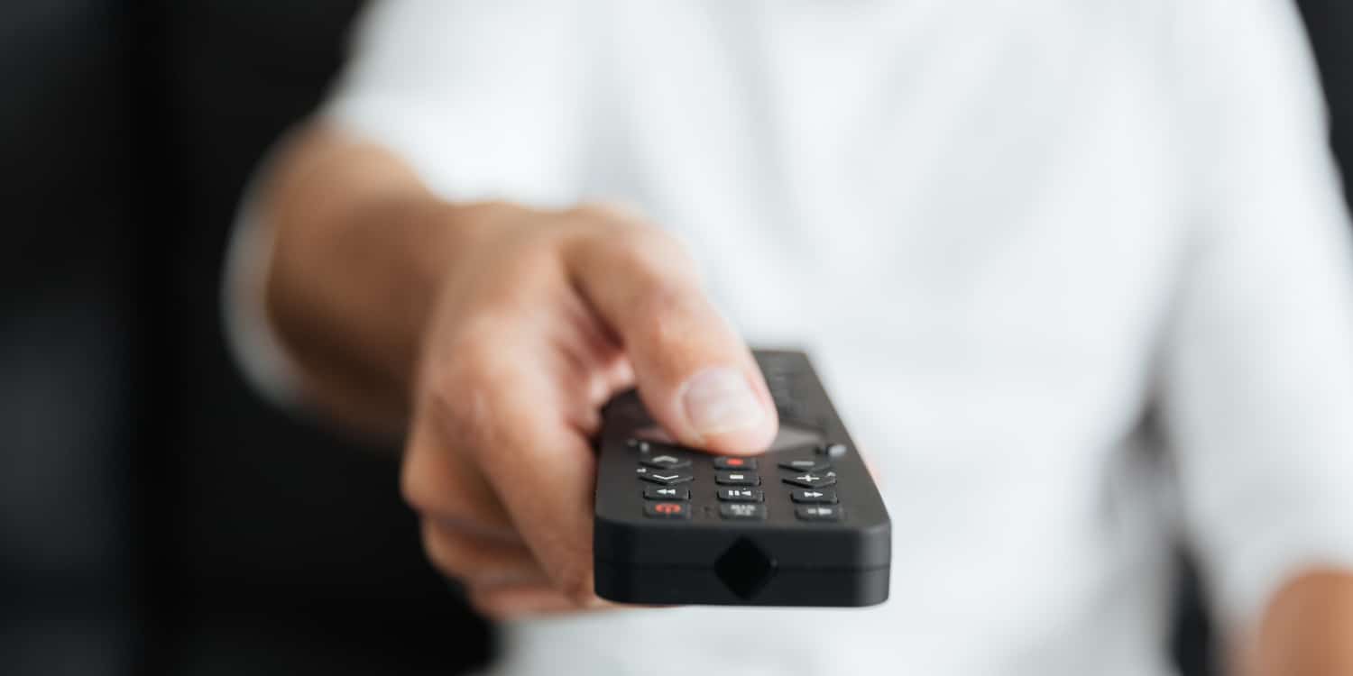 uomo cambia canale con telecomando